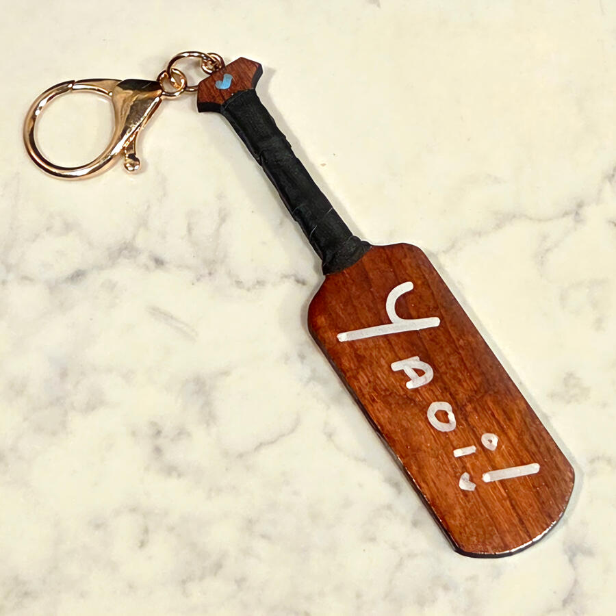 [V2] Wooden double sided Yaoi/Yuri Paddle Keychains; YAOI SIDE; CNC cut solid Applewood, with an American Walnut Stain, hand-sized black handle tape, white acrylic hand lettering, UV-resistant topcoat polyurthane, and white gold hardware.