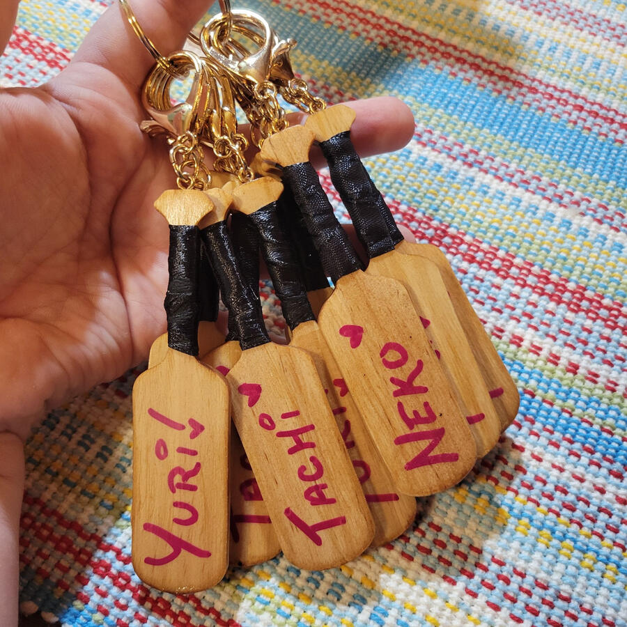 [V1] Wooden Yuri Paddle Keychains; CNC cut pine with a dark pecan stain, black ribbon handle wraps, magenta acrylic hand lettering, and rose gold hardware.