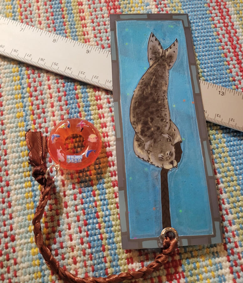 Seal Tug-of-War bookmark; translucency done with tissue paper. Designed, printed, Hand cut, glued, hot laminated and assembled in-house